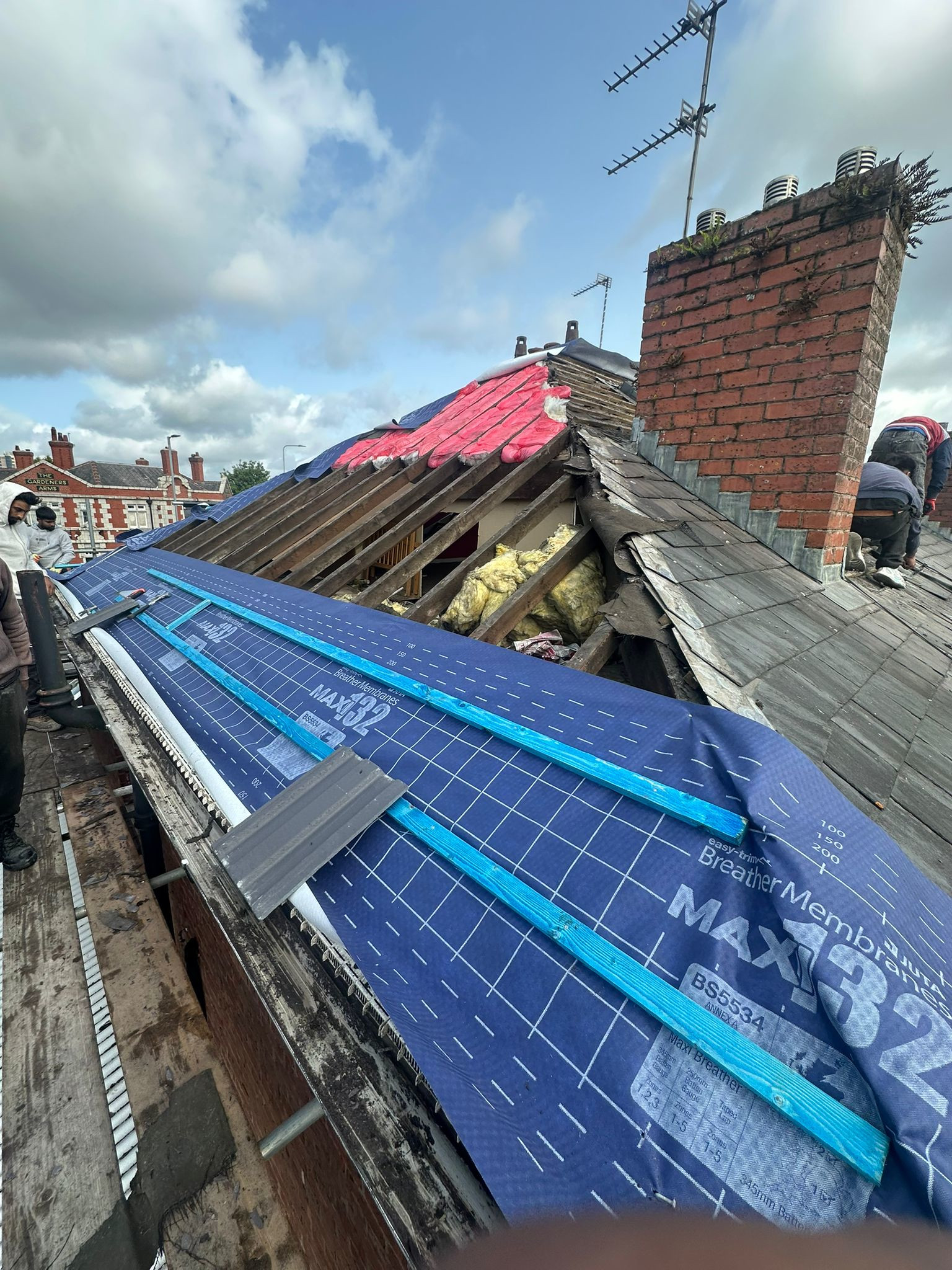 Roofers repairing a leaking slate roof in Timperley east Manchester.